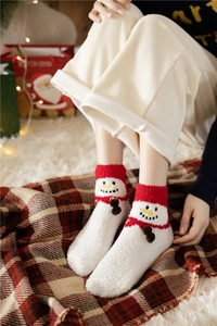 Close-up of thick coral fleece Christmas socks with snowman pattern in warm festive setting