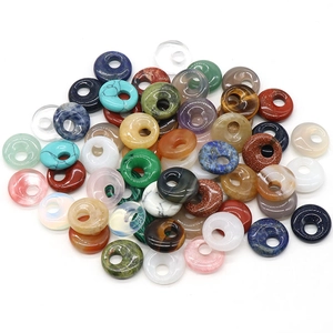Colorful natural crystal stone donut charms scattered on white background in top view