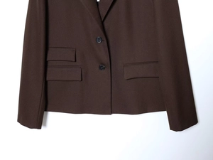 Detail of brown blazer showing two-button closure and symmetrical flap pockets