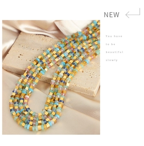 Détail d'un collier en acier titane avec perles colorées et cubes dorés
