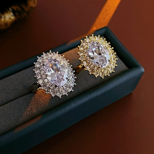 Detail of gold and silver plated oval halo rings with pavé cubic zirconia in a jewelry box