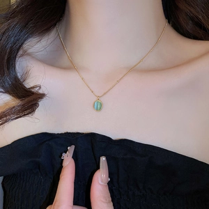 Close-up of a green oval opal pendant on a gold stainless steel necklace worn by a model