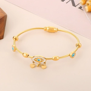 Close-up of golden Evil Eye bracelet with heart charms and twisted wire texture