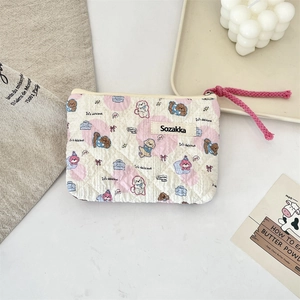 Macro detail of quilted floral pouch featuring cute dog illustrations and woven zipper pull