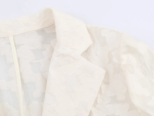 Détail macro du col et de la dentelle crème sur une veste cintrée pour femme