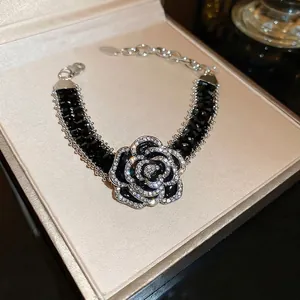Elegant black camellia flower bracelet with rhinestones on a premium jewelry box