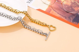 Dettaglio di bracciali a catena bicolore con chiusura a cuore e maglie in stile industriale