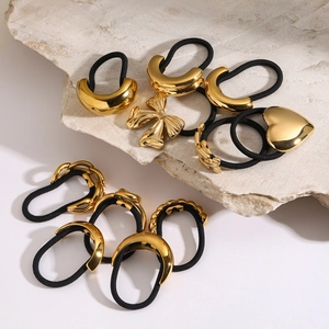 Minimalist gold metal hair ties with heart and bow charms on black elastic bands