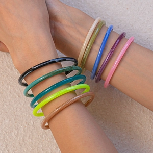 Close-up of stacked colorful acrylic bangles in assorted marble shades on a model