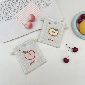 Close-up of cute embroidered apple and peach fruit patterns on checkered storage pouches