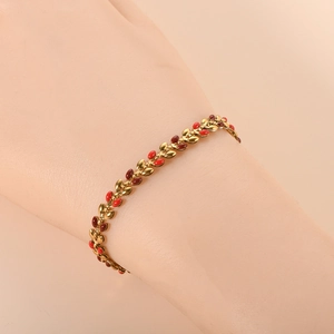 Detailed close-up of 18K gold olive leaf bracelet with red enamel inlay on wrist
