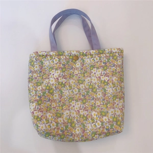 Detailed view of floral canvas lunch bag with purple handles and gold snap fastener