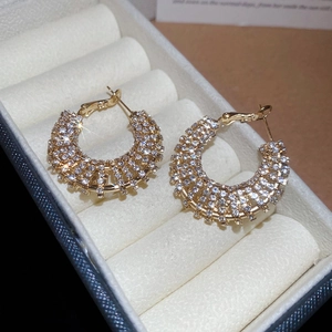 Detail of sparkling gold-tone earrings with micro-inlaid rhinestones in a velvet box