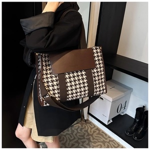 Detail of vintage houndstooth tote bag with leather trim and stylish logo on the flap