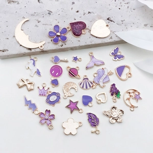 Flat lay of diverse purple and gold enamel charms including moons, stars, and hearts