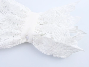 Detailed macro view of white lace cuffs with intricate patterns and a round button closure