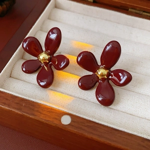 Detailed view of red floral earrings with gold centers in a luxury velvet jewelry box
