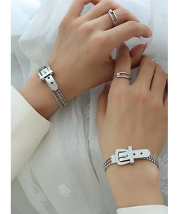 Close-up of silver-plated buckle bracelet and pearl ring on white lace background