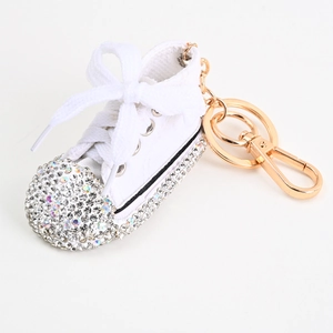 Detail eines weißen Leinwand-Sneaker-Schlüsselanhängers mit Strasssteinen und Goldring