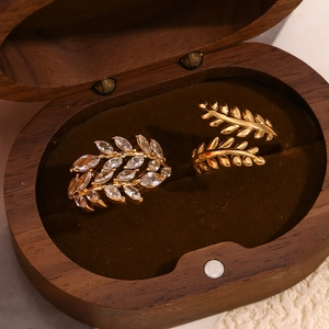 Detalle de anillos de rama bañados en oro 18K con circonitas en caja de madera