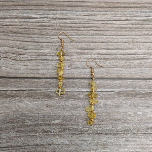 Detail of handmade bohemian earrings with natural yellow citrine stones and gold beads