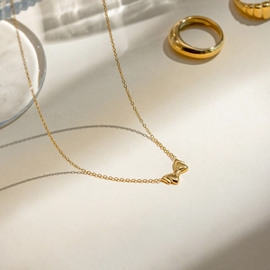 Detailed close-up of a high-polish 18k gold-plated stainless steel bow pendant necklace