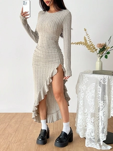 Detail of knitted khaki dress featuring slim waist pleats and asymmetric ruffled slit hem