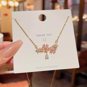 Close-up of golden cherry blossom necklace with pink zircons and a teardrop crystal charm