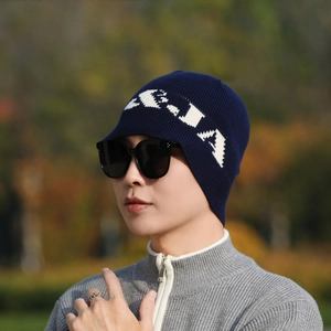 Navy blue knitted beanie with white A-JA jacquard logo worn by male model outdoors