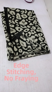 Detail shot of the overlock stitched edge on a thick leopard print cashmere-like scarf