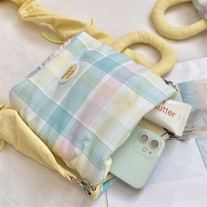 Detail showing the internal storage space of a plaid water bottle bag with a phone and cream