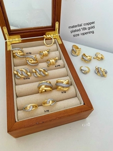 Detail of copper 18k gold plated open rings with zircon inlay on a wooden box