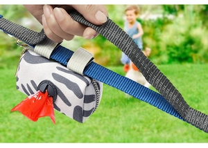 Detail of black and white striped pet waste bag dispenser on a blue leash outdoors