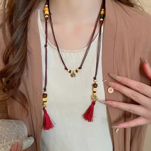 Ethnic wood bead necklace with red tassels and gold pendants for a bohemian style