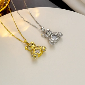 Close-up of gold and silver teddy bear pendants with clover-shaped crystals on a tray