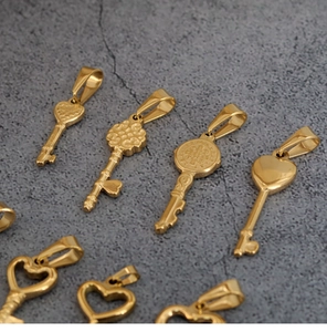 Close-up of assorted gold-colored vintage heart key pendants on a textured stone surface