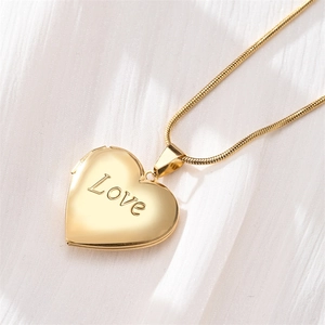 Detailed close-up of golden heart locket necklace with Love engraving on snake chain