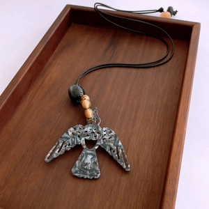 Vue détaillée du pendentif oiseau tribal avec texture marbrée sur plateau en bois