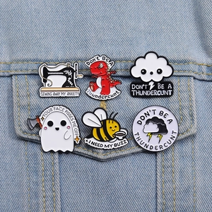 Set of creative colorful enamel lapel pins with dinosaur, ghost and bee on denim fabric