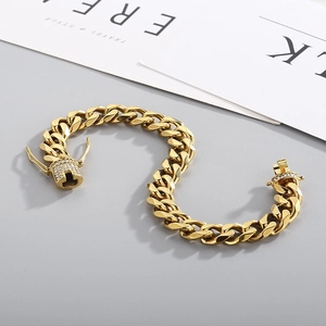 Detail of gold Cuban chain bracelet with iced out diamond safety clasp over lifestyle book