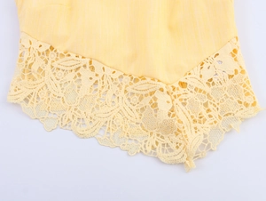 Detail of yellow textured fabric hem with intricate floral lace trim for elegant look