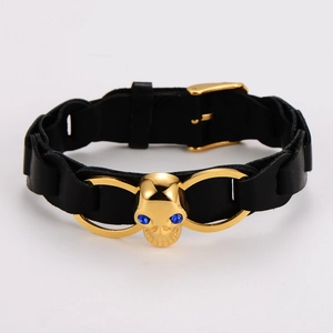 Detail of punk leather bracelet featuring a golden skull with blue rhinestone eyes