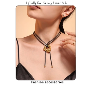 Detail of a wavy golden heart pendant on a black leather cord with elegant model styling