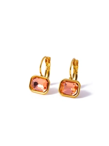 Macro shot of gold square earrings with rectangular pink crystals on white backdrop