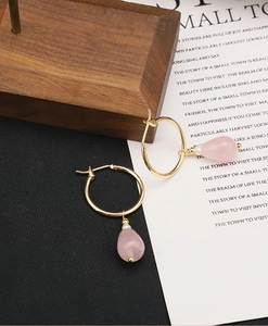 Detail of pink teardrop crystal earrings with gold hoop on a wooden vintage display