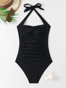 Chic black halter one-piece swimsuit with ruching detail on a summer beach flat lay