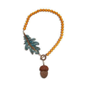 Vintage crystal beaded necklace with leaf and acorn charms on a white background