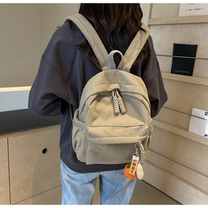 Close-up of light khaki corduroy backpack featuring a cute persimmon plush charm detail