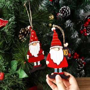 Two wooden Santa Claus ornaments hanging on a Christmas tree with pine cones and berries