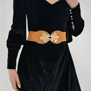 Detail of brown elastic waist belt with gold floral metal buckle on velvet dress